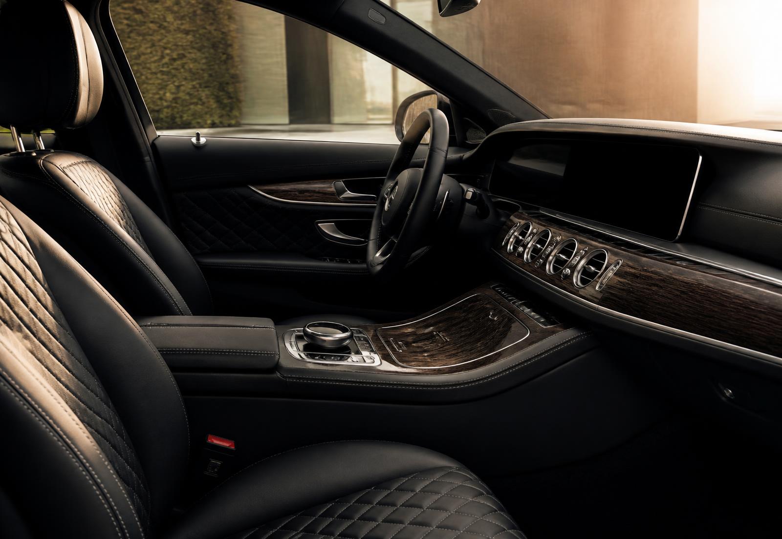Immaculate black quilted leather luxury sedan interior with dark wood trim in warm side light